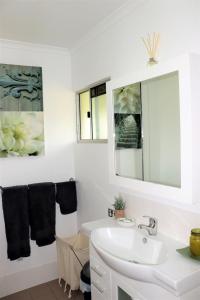 a white bathroom with a sink and a mirror at Watersons at Airlie Central Apartments in Airlie Beach