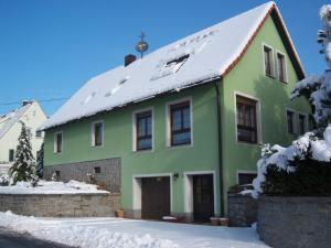 a green house with snow on the roof at Ferienwohnung "An der St. Ludmila" in Crostwitz