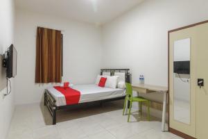 sypialnia z łóżkiem, biurkiem i lustrem w obiekcie RedDoorz near AP Pettarani 3 w mieście Pampang