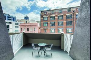 un balcón con 2 sillas y una mesa y un edificio en Central Studio Hotel Sydney, en Sídney