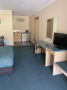 a hotel room with a bed and a desk with a computer at Arthur Phillip Motor Inn in Cowes