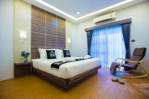 a bedroom with a large bed and a chair at The S.G Hotel in Buriram
