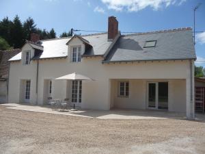 a white house with an umbrella in front of it at La vieille maison in Cour-Cheverny