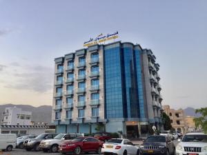 un bâtiment avec des voitures garées dans un parking dans l'établissement Diwan Al Amir, à Khasab