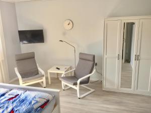 a living room with two chairs and a clock on the wall at MeFo in Heiligenhafen