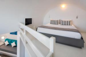 a white bedroom with a bed and a staircase at Apanemo Hotel & Suites in Akrotiri
