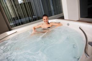 a man is sitting in a jacuzzi tub at Sport & Relax Hotel Davidek in Trutnov