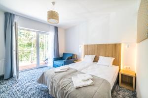 una habitación de hotel con una cama grande y una silla azul en WYDMA Resort Medi & SPA - Normobaria, en Mrzeżyno