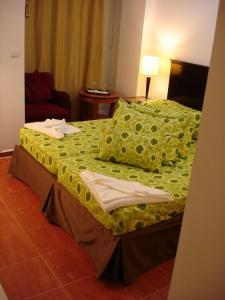 a hotel room with a bed with green sheets and pillows at Villa Mar Bella in Costinesti +32 photos