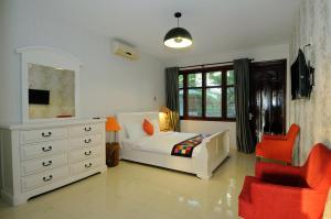 a bedroom with a bed and a dresser and red chairs at Ananas Beach Hotel in Vung Tau