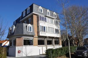 ein großes weißes und rotes Gebäude mit schwarzem Dach in der Unterkunft Hotel Bon Accueil in De Haan