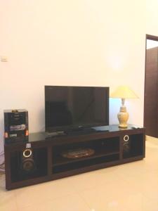 a entertainment center with a flat screen tv and a lamp at Fams Homestay by FH Stay in Yogyakarta