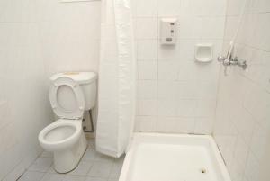 a white bathroom with a toilet and a shower at Rumbia Resort Villa Paka in Paka