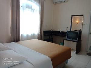 a hotel room with a bed and a television at Hotel Monika in Rantepao
