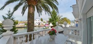 a balcony with a palm tree and a view of the water at Villa Requesens on Canal in Empuriabrava