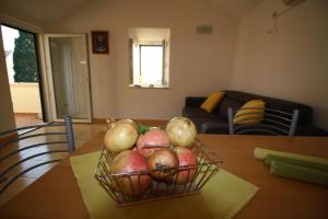 a basket of pomegranates and apples on a table at Apartmani Šolo in Sumartin +12 photos