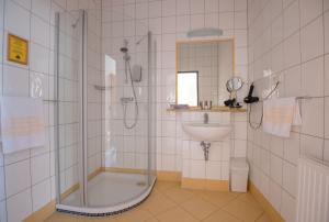 ein Bad mit einer Dusche und einem Waschbecken in der Unterkunft Der Marienhof Hotel Garni in Graz