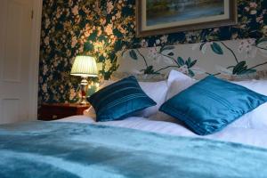 a bedroom with a bed with blue pillows at Killyliss Country House B&B in Lisnalong