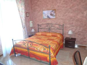 a bedroom with a bed with a orange and yellow blanket at B&B Casa Di Mari in Aci SantʼAntonio