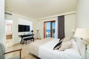 a bedroom with a bed and a desk and a television at Hotel Santa Marta in Lloret de Mar