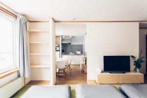 a living room with a television and a kitchen at The Apartment Hotels YAMA in Sapporo