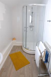 a bathroom with a shower and a yellow rug at The Crows Nest Holiday Home in Burry Port