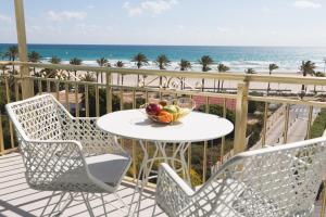 a bowl of fruit on a table on a balcony with the beach at Hotel Almirante in Alicante