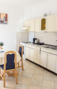 a kitchen with white cabinets and a table and chairs at Apartment Sv. Marak in Risika