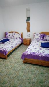 two beds in a room with purple comforter at Casa cu Castan in Eforie Nord