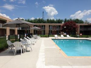 a pool with chairs and an umbrella next to a building at Ramada by Wyndham Wytheville in Wytheville