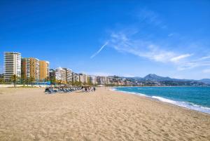a beach with chairs and the ocean and buildings at Diamond Apartments Puerto De Malaga in Málaga