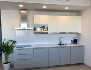 una cocina blanca con armarios blancos y fregadero en Diamond Apartments Puerto De Malaga, en Málaga