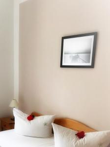 ein Bett mit weißen Kissen und einem Bild an der Wand in der Unterkunft FerienResidenz MüritzPark in Röbel