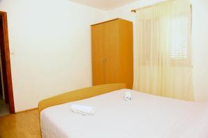 a bedroom with a white bed and a wooden cabinet at Apartments Tonia br. 1 in Zavalatica