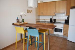 a kitchen with yellow and blue chairs at a wooden table at VILLA MOLEIRO- LA TEJITA in La Tejita