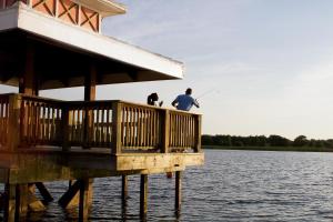dos personas pescando en un muelle en el agua en Summer Bay Orlando by Exploria Resorts en Orlando