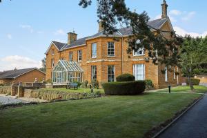 uma grande casa de tijolos com um relvado verde em frente em Sedgebrook Hall em Northampton