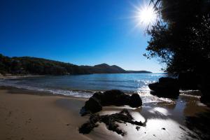 a beach with rocks in the water and the sun at Grand Hotel Il Ninfeo in Gaeta