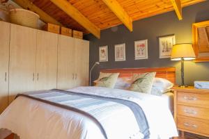a bedroom with a white bed and a wooden ceiling at Theebos in Strand