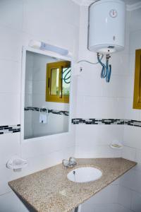 bagno con lavandino e specchio di Hôtel La Couronne RW a Yaoundé