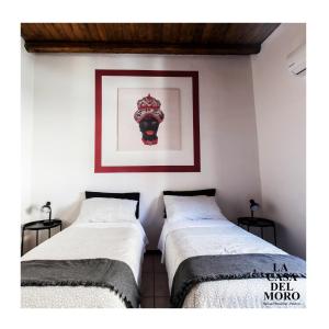 two beds in a room with a picture on the wall at La Casa del Moro in Palermo