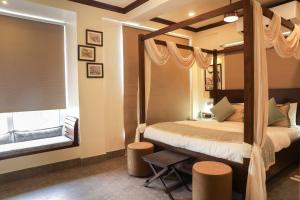 a bedroom with a four poster bed and a mirror at The Mandeville in Kolkata