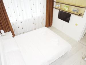 Cama blanca en habitación con TV en Smart Apartament en Piatra Neamţ