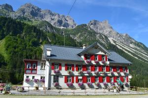 ein Haus mit roten Rollläden vor einem Berg in der Unterkunft Landhaus Bad Hopfreben in Schoppernau