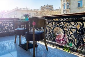 balkon z 2 krzesłami i ogrodzeniem w obiekcie Travel Inn Hostel w mieście Baku