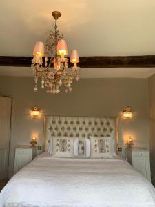 una camera da letto con un letto grande con un lampadario di Pytts House Boutique Bed & Breakfast a Burford