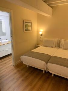 two beds in a small room with a bathroom at Casa Herreria in Caldas de Reis