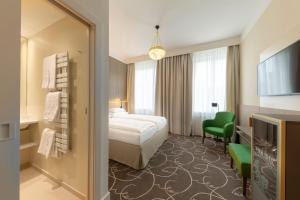 ウィーンにあるホテル エァッツヘァツォーク ライナーのベッドと緑の椅子が備わるホテルルームです。
