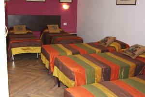 a room with three beds with colorful blankets at Hotel San Lorenzo in Florence