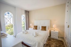 een witte slaapkamer met een groot wit bed met 2 kussens bij Beach View Playa Del Moral in Estepona